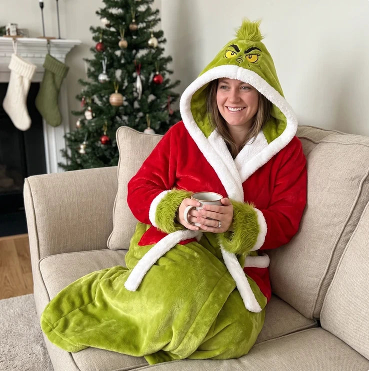 Personne portant le peignoir-couverture rouge et vert avec capuche grincheuse, assise sur un canapé